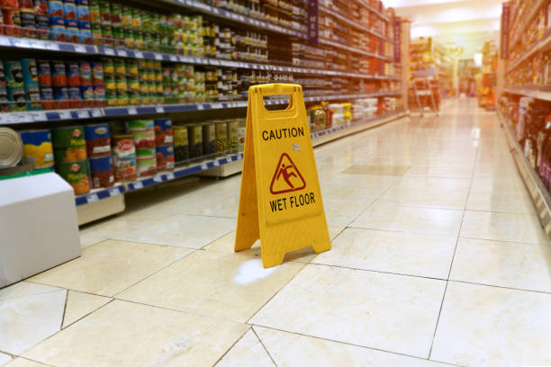 close up Yellow sign - caution. Wet floor is in the supermarket against the background of blurry products standing on the shelves wet stock pictures, royalty-free photos & images