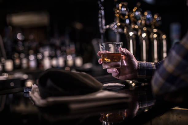 istock Old man holding whiskey glass in a dark bar 916088178