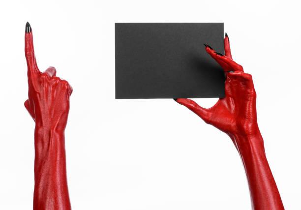 istock Halloween theme: Red devil hand with black nails holding a blank black card on a white background 916091198