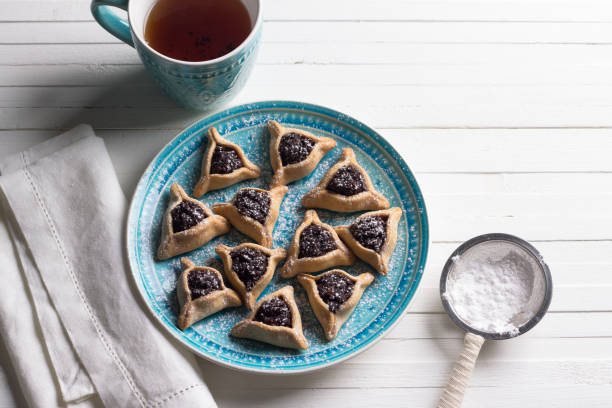 hamantashen 쿠키 또는 귀 함 안의 양 귀 비 씨와 차 한 잔과에 건포도 삼각형 쿠키 - purim high angle view cookie food 뉴스 사진 이미지