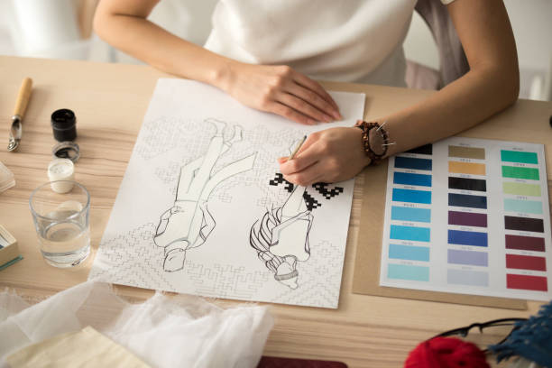 istock Female designer hands painting embroidery pattern scheme on fash 916092410