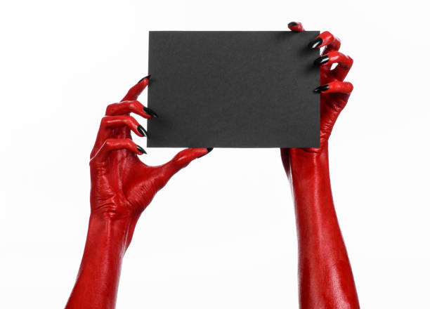 istock Halloween theme: Red devil hand with black nails holding a blank black card on a white background 916097968