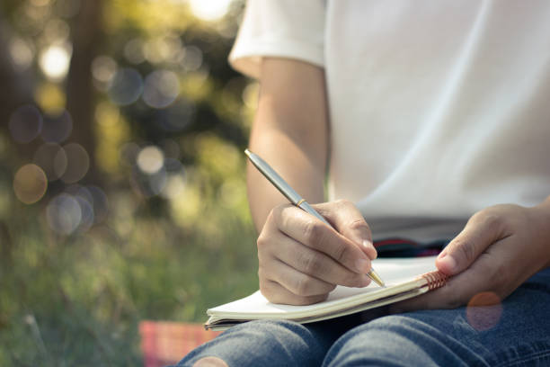 close up young women writing on notebook in park, concept in education and knowledge stock photo