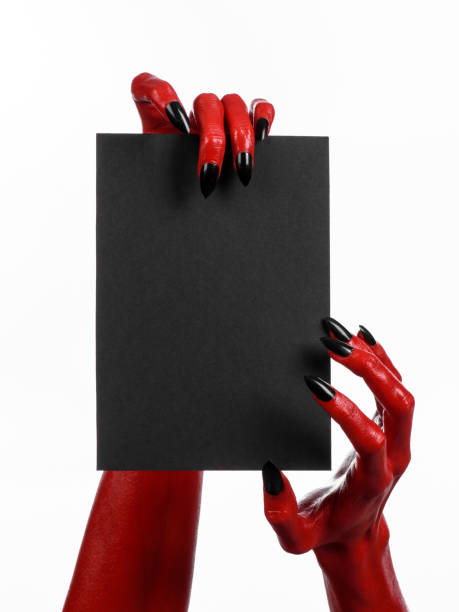 istock Halloween theme: Red devil hand with black nails holding a blank black card on a white background 916107550