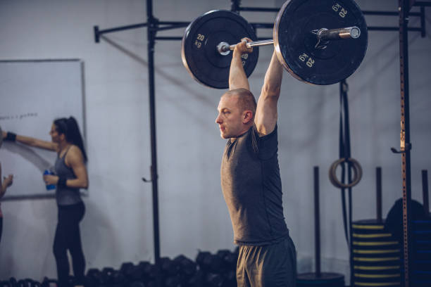 istock Sporty man lifting weights in the gym 916109402