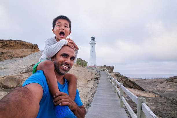 padre e hijo tomando selfie con castlepoint faro de fondo. - castlepoint fotografías e imágenes de stock