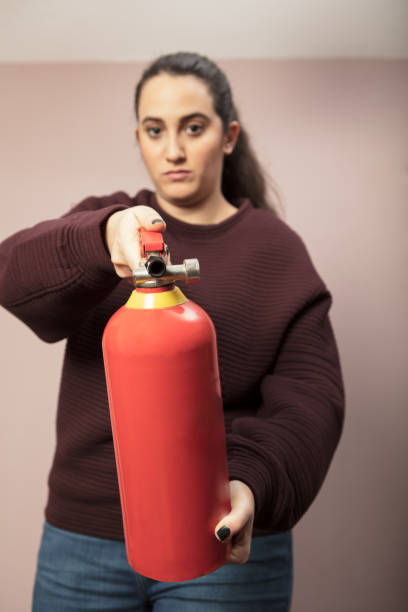 istock Young woman pointing a fire extinguisher forwards 916113012