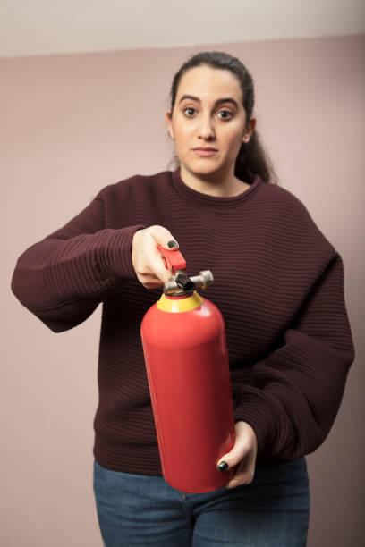 istock Young woman pointing a fire extinguisher forwards 916113016