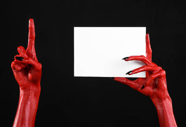 istock Halloween theme: Red devil hand with black nails holding a blank white card on a black background 916113158