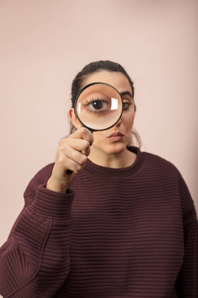 istock Woman looking through magnifying glass 916115728