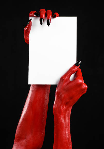 istock Halloween theme: Red devil hand with black nails holding a blank white card on a black background 916116034