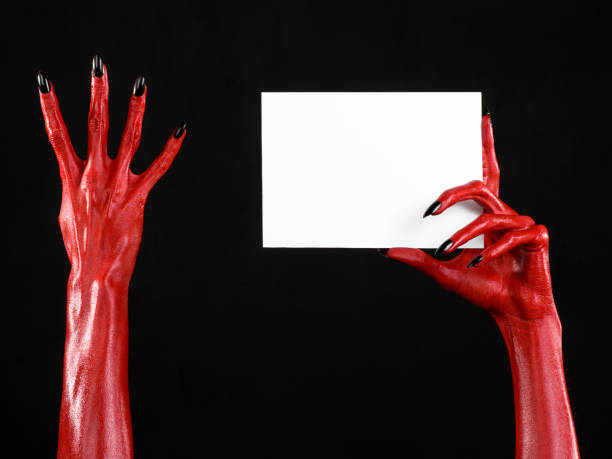 istock Halloween theme: Red devil hand with black nails holding a blank white card on a black background 916116264