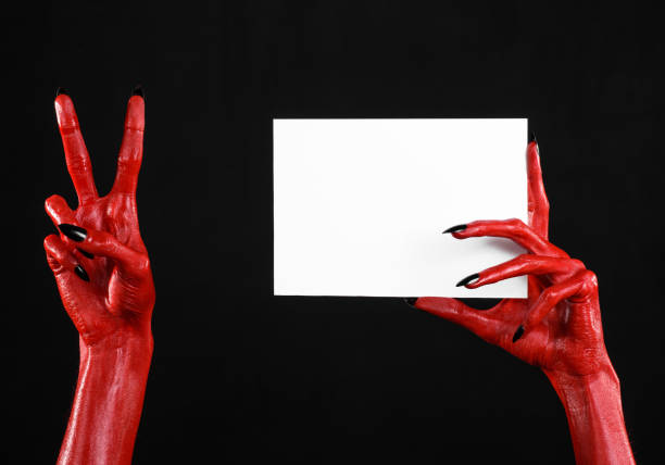 istock Halloween theme: Red devil hand with black nails holding a blank white card on a black background 916117038