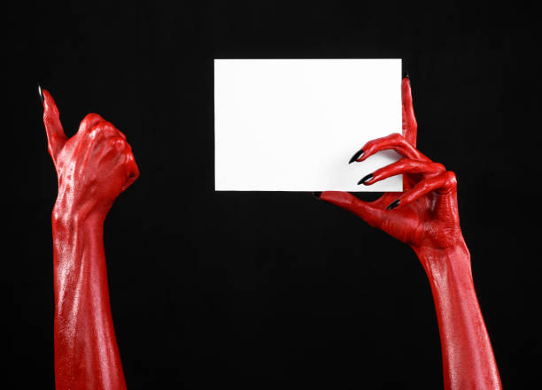 istock Halloween theme: Red devil hand with black nails holding a blank white card on a black background 916117182