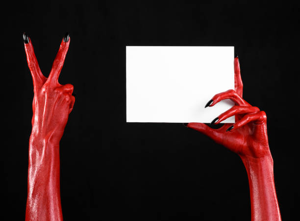 istock Halloween theme: Red devil hand with black nails holding a blank white card on a black background 916118256