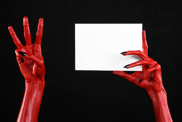 istock Halloween theme: Red devil hand with black nails holding a blank white card on a black background 916120360