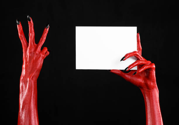 istock Halloween theme: Red devil hand with black nails holding a blank white card on a black background 916120500