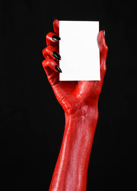 istock Halloween theme: Red devil hand with black nails holding a blank white card on a black background 916120636