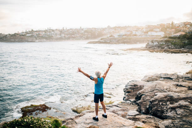 istock Senior runner raises arms after run 916124698