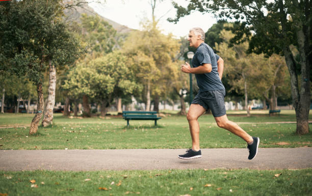 Living on the healthy side of life Shot of a senior man out for a run in the park jogging stock pictures, royalty-free photos & images