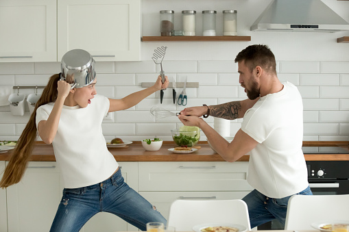 Funny Couple Having Fun Fighting With Kitchen Utensils Cooking T Stock  Photo - Download Image Now - iStock