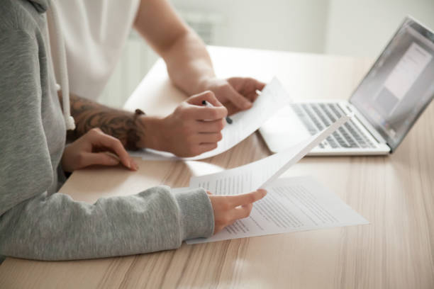 Couple holding reading documents at home with laptop, close up
