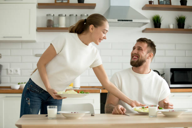 séduisante femme servir des aliments cuits pour mari dans la cuisine - bon appetite photos et images de collection