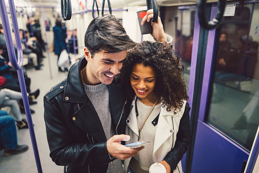 Young couple using smartphone while traveling with the subway