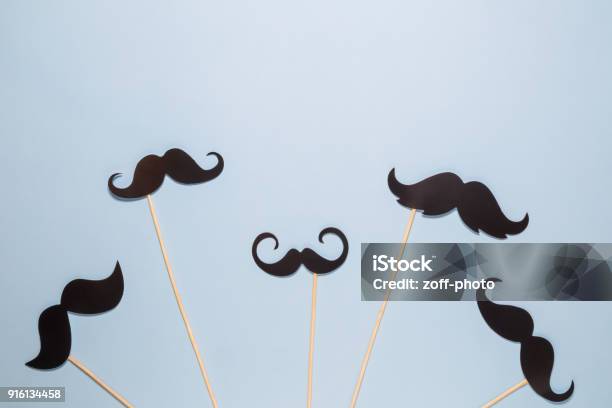 Flat Lay Of Different Kinds Of Paper Mustaches Against Blue Background Stock Photo - Download Image Now