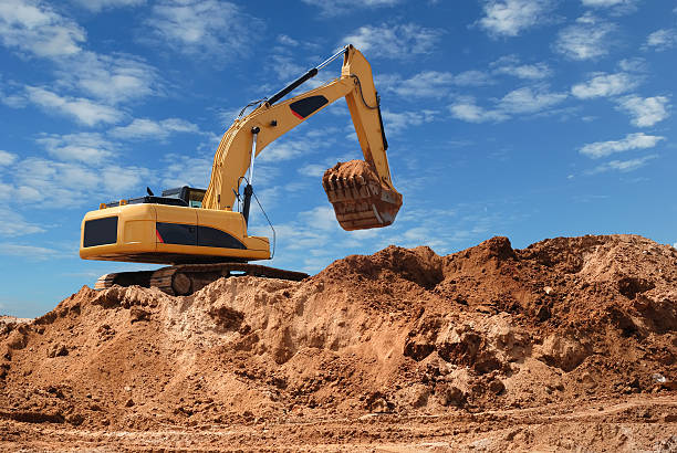 An excavator digging up dirt in a sand pit stock photo