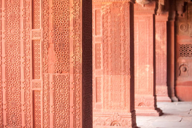 Shaped arch adorned with carved details in red sandstone - exterior detail of Jahangiri Mahal in Agra Fort, Uttar Pradesh, India. It was built by Mughal Emperor Akbar. UNESCO World Heritage site.