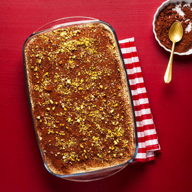 sobremesa tradicional italiana com café, cacau e mascarpone bolo de tiramisu de queijo em uma panela de forno num vermelho. polvilhado com pistache - biscotti cookie chocolate pistachio - fotografias e filmes do acervo