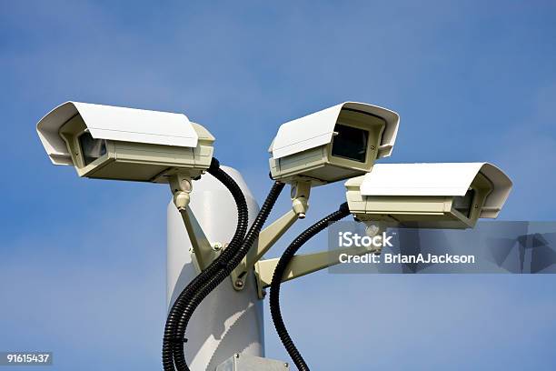 Three Surveillance Cameras Against A Blue Sky Stock Photo - Download Image Now - Analyzing, Big Brother - Orwellian Concept, Blue