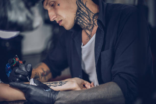 istock Artist making tattoo on customer's hand 916155604