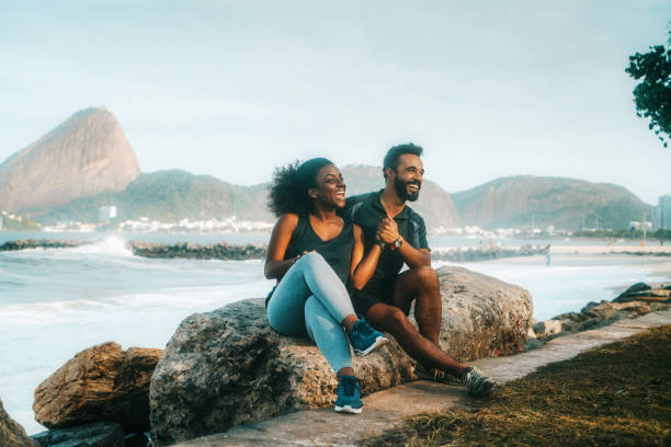 istock sporty couple sitting on rock at beach 916155992