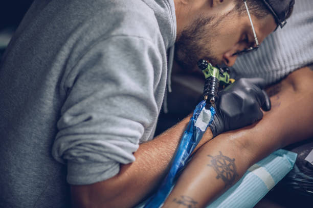 Artist making tattoo on customer's hand in studio