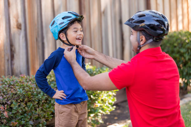 Father and Son Sports Safety High quality stock photo of a father helping his son put on an athletic sports helmet for bicycle riding and skateboards. cycling helmet photos stock pictures, royalty-free photos & images