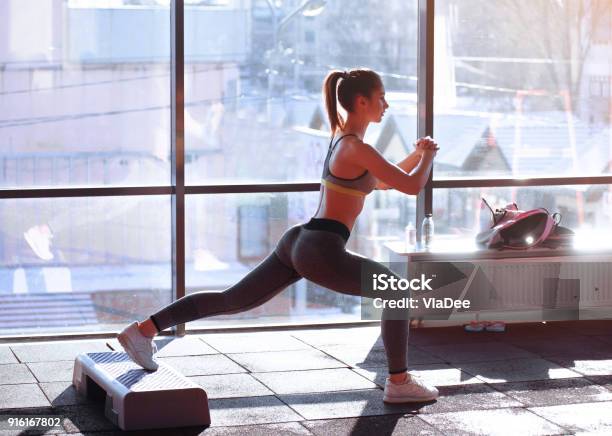 Portrait Of Young Sporty Girl Doing Stretching Exercise Near Large Window Stock Photo - Download Image Now