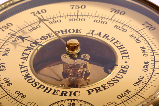 The old yellow-brown aneroid barometer in wooden body close-up