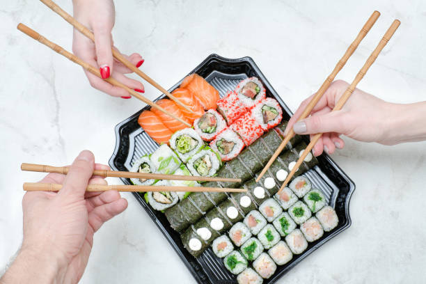 istock Three hands with chopsticks and sushi set. Top view 916180052