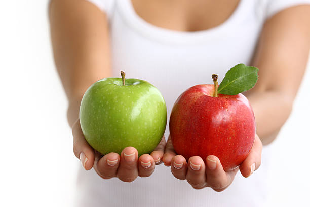 manos sosteniendo rojo y verde manzana - apple granny smith apple green leaf fotografías e imágenes de stock