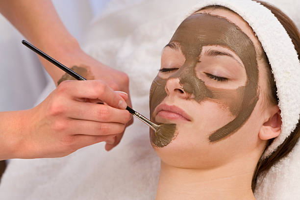 Mulher com Máscara de Chocolate facial do Terapeuta de Beleza no Spa aplicação - fotografia de stock