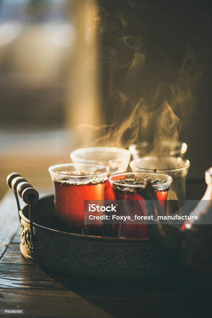 Traditional hot steaming Turkish tea in tulip glasses Traditional hot steaming Turkish tea in tulip glasses with copper pot in vintage tray Afternoon Tea Stock Photo