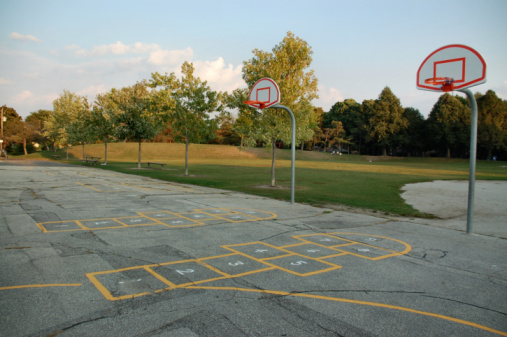 Schoolyard with basketball nets and hopscotch games.