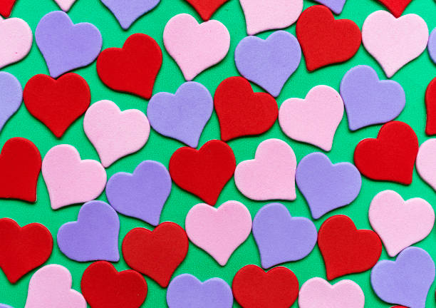 istock Pattern of bright multicolored hearts on a green background. Valentines day card, image for background. 916189022