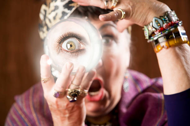 Blurred gypsy with eye magnified on crystal ball Female gypsy fortune teller holding a crystal ball to her eye runes photos stock pictures, royalty-free photos & images