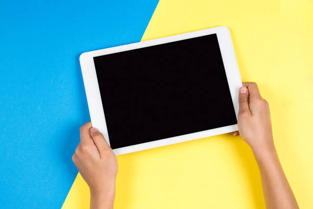 istock Kid hands with tablet computer on blue and yellow background 916197806