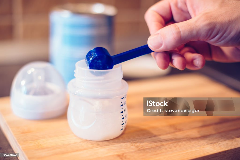 Father making baby formula in milk bottle Father making baby formula in milk bottle for a newborn baby feed Infant Formula Stock Photo