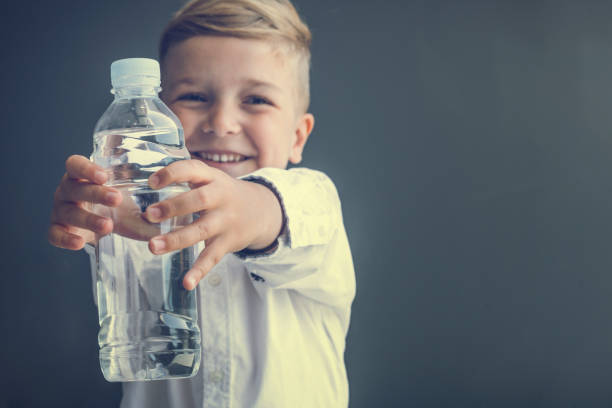 heureux garçon tenant bouteille d’eau. - water child bottle little boys photos et images de collection