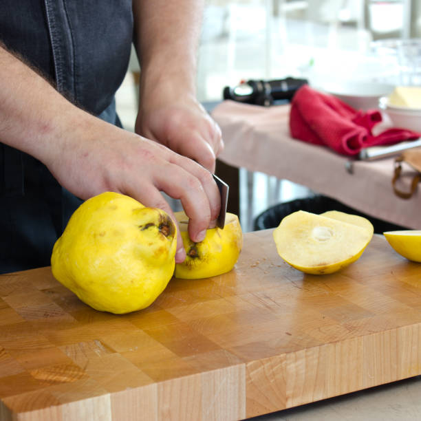 mani maschili tagliano grandi mela cotogne gialle su un tagliere in legno - 1466 foto e immagini stock